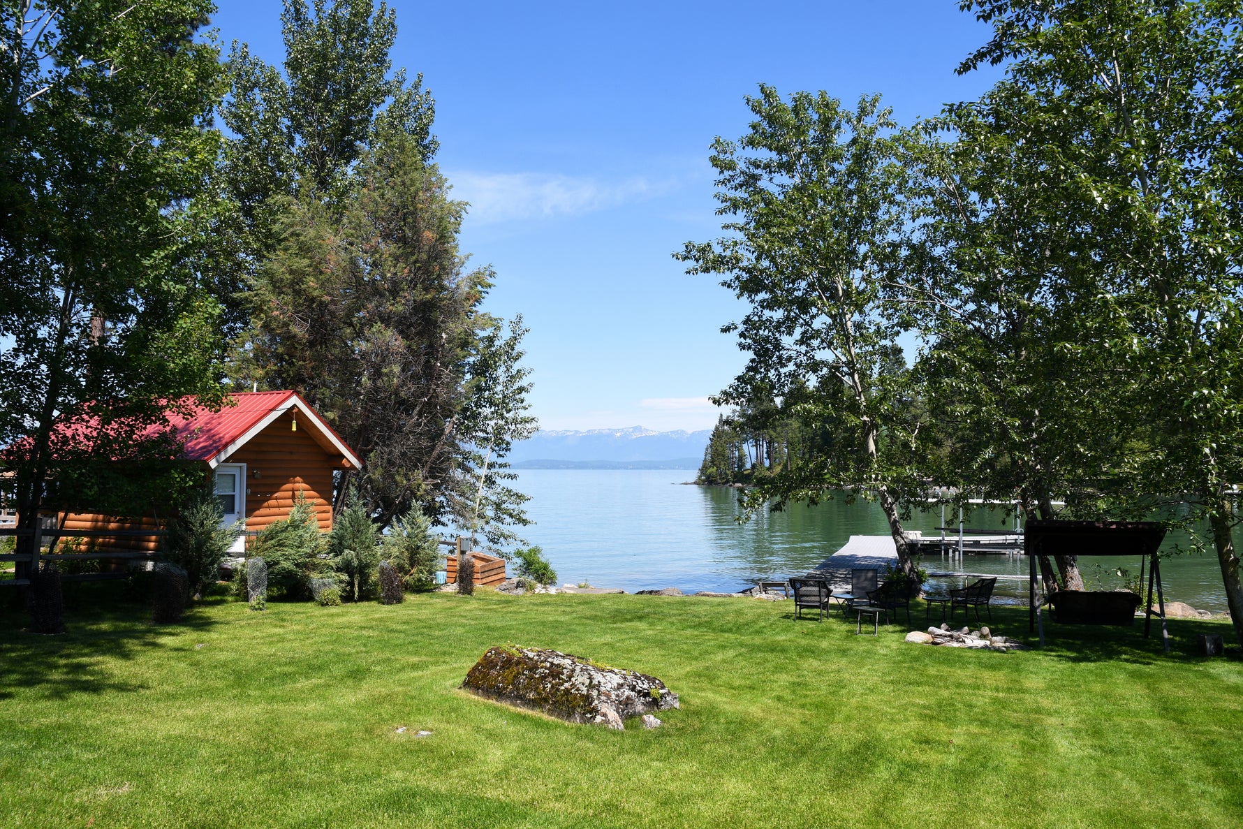 Lush green lakeside residential yard with private dock and log cabin, showcasing the ideal results of Lifetyme Sandy Soil Seed Mix